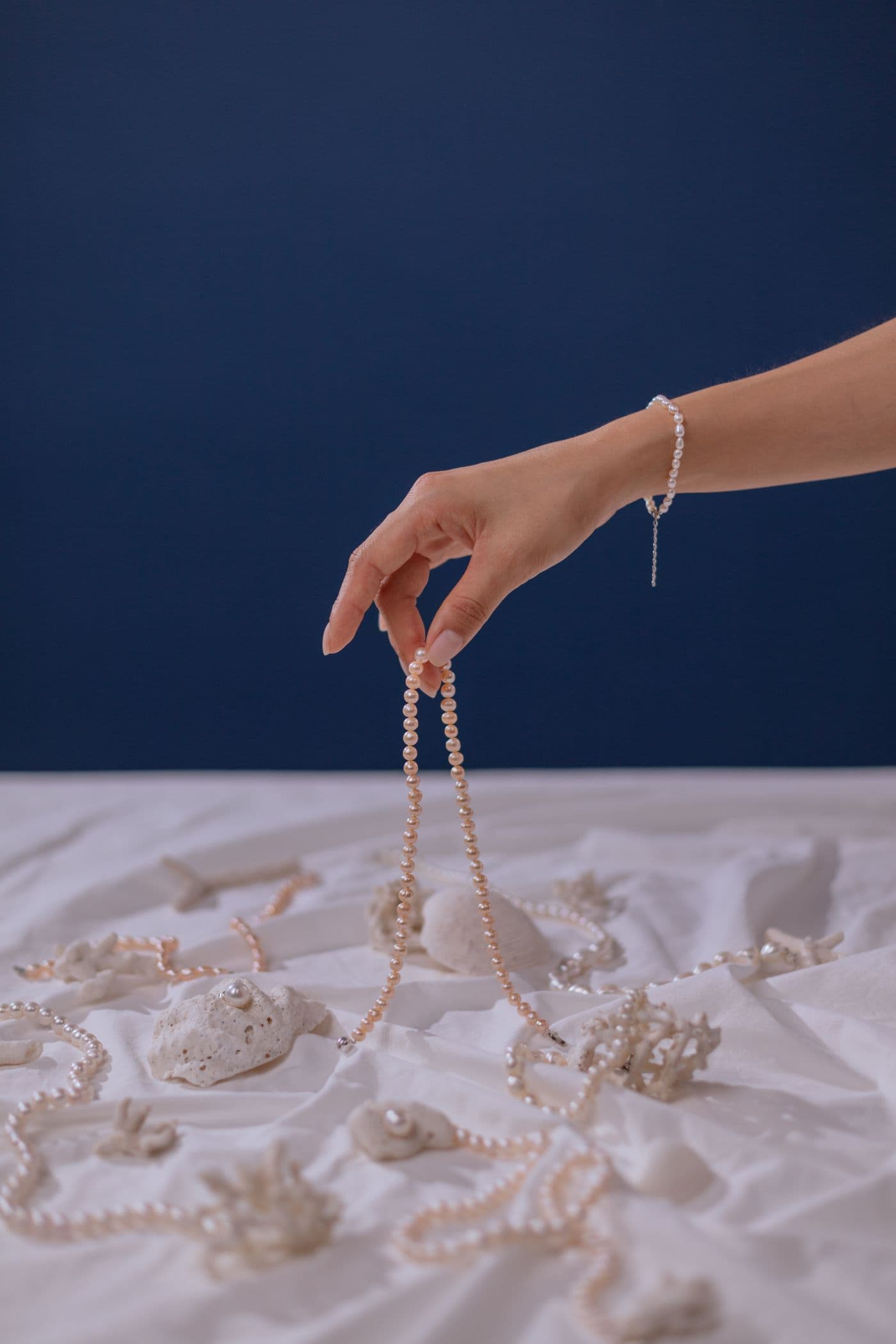 A hand gently lifting a finished pearl strand