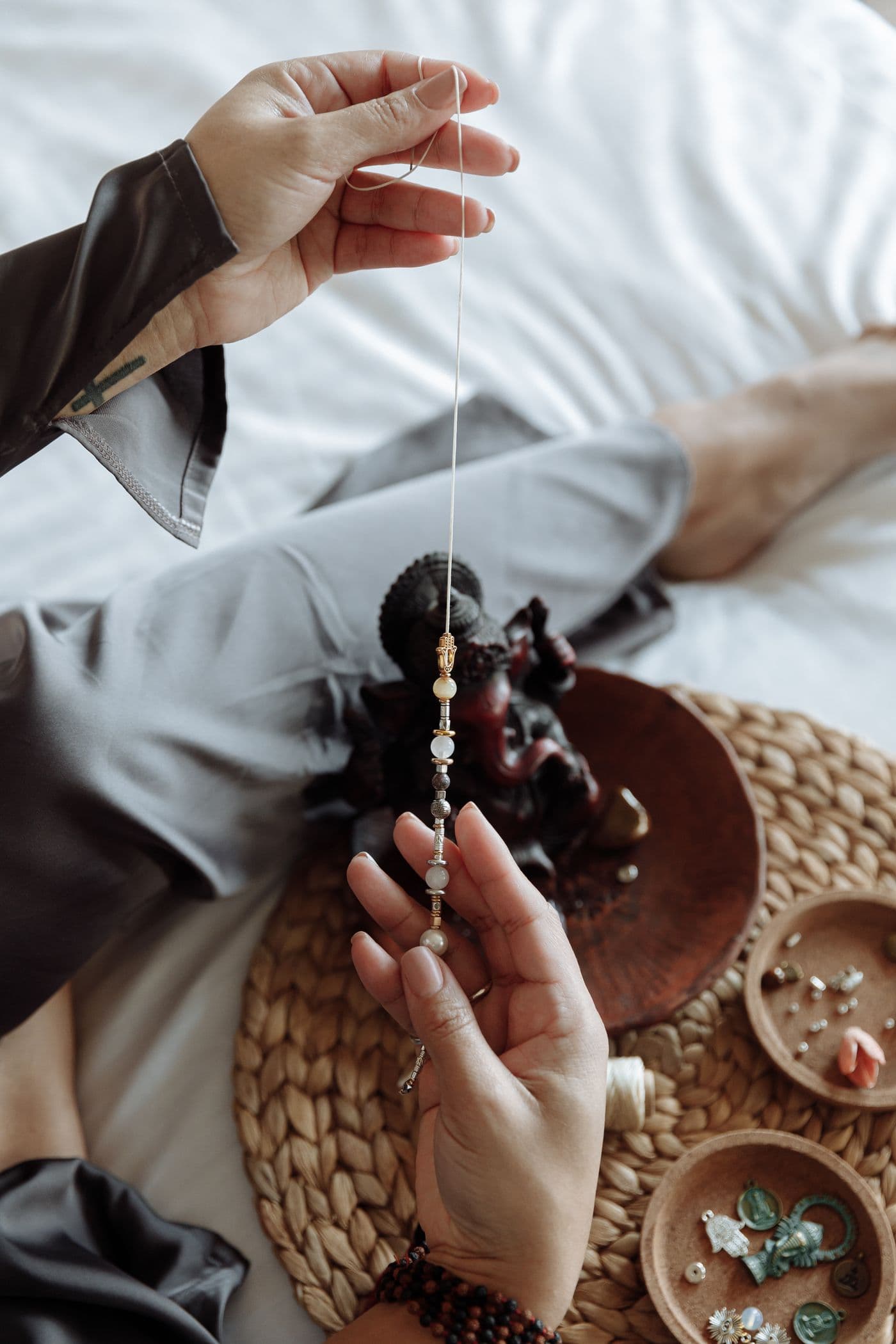 Hands tying a hand-knot between beads on a silk thread