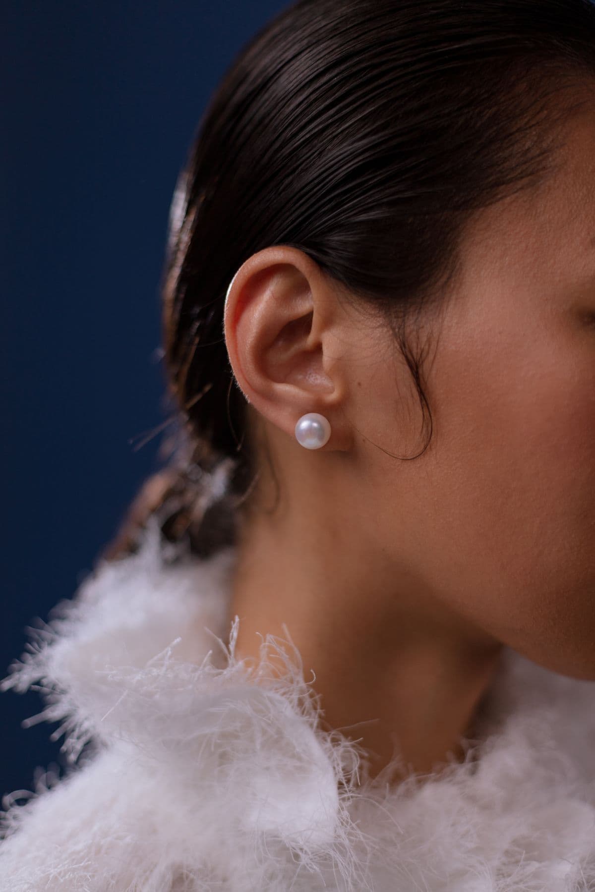 Close-up of a woman wearing a white pearl earring
