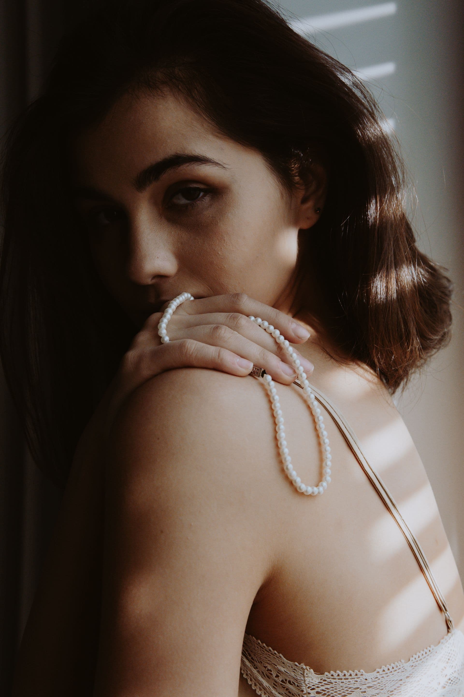 A woman glancing back over her shoulder, wearing a pearl necklace